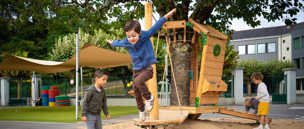 Kinder spielen auf einem Arborea Play® Spielgerät aus Naturholz im naturnahen, grünen Schulhof (Oasis-Schulhof)