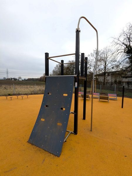 Steile Parcourswand mit Klettergriffen und Aufstiegselementen auf Fallschutzboden