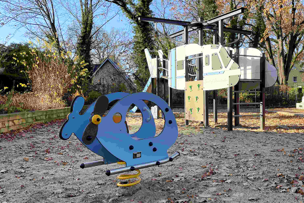 Spielplatz in Berlin-Steinstücken mit Wipptier in Hubschrauberform im Vordergrund und thematischem Kletterspielgerät im Hintergrund