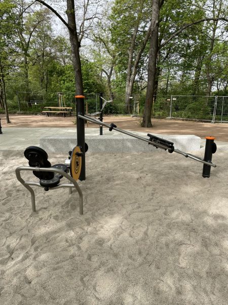 Rudergerät und Beintrainer/Fahrrad für den Outdoor-Einsatz auf Sandfläche im Mariannenpark Leipzig, eingebettet in eine grüne Parklandschaft.