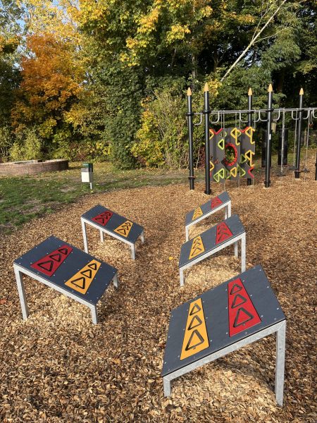 Fünf schräg angeordnete Sprungplattformen eines „5-Sprung“-Moduls auf einem Holzhackschnitzelboden, dahinter ein Kletter- und Hangelbereich, umgeben von herbstlichen Bäumen.