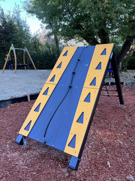 Kletterrampe mit Seil aus der ACTI'Ninja-Serie im Eichpark Sottrum, montiert auf Fallschutzbelag aus Holzhackschnitzeln, im Hintergrund eine Nestschaukel.