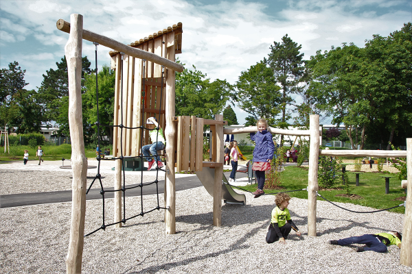Kinder spielen auf einem naturnahen Klettergerät aus Holz mit Rutsche und Netz im Generationenpark Philippsburg.