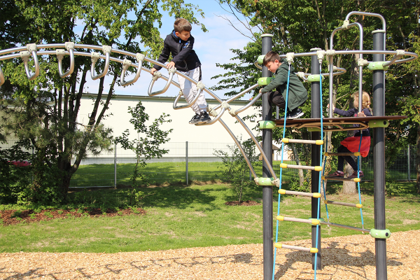 Kinder klettern und balancieren auf einem modernen IXO-Klettergerät aus Metall mit verschiedenen Aufstiegen und geschwungenem Hangelbogen.