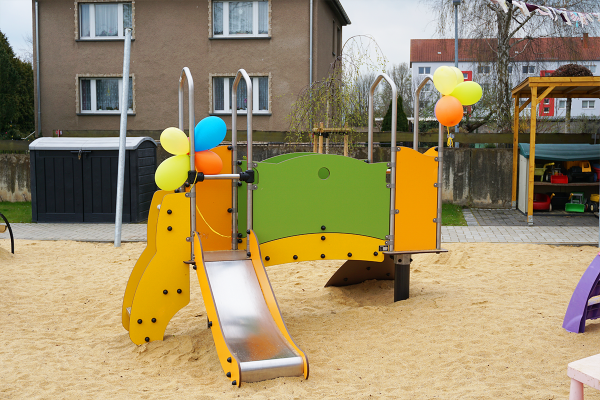 Kleinkindgerechtes Spielgerät mit Rutsche, bunten Seitenteilen und Ballons auf einem Sandspielbereich, ideal für erste Bewegungserfahrungen.
