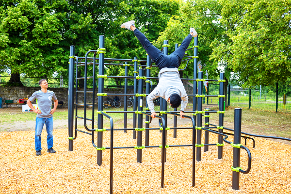Sportler trainiert an inklusiver Calisthenics- und Street-Workout-Anlage mit Handstandelementen im öffentlichen Raum