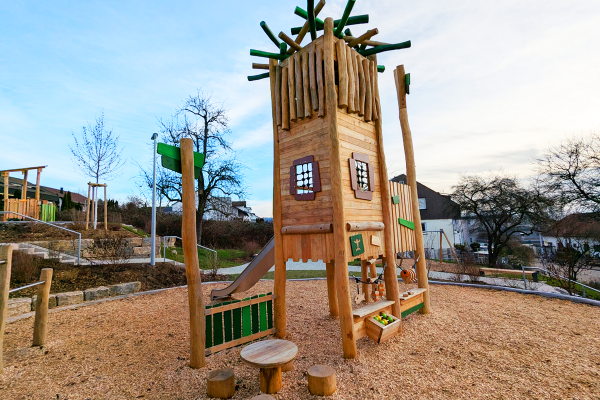 Naturholz-Spielturm mit Rutsche, Sandspielbereich und Sitzgruppe auf einem nachhaltig gestalteten Quartiersspielplatz in Eislingen.