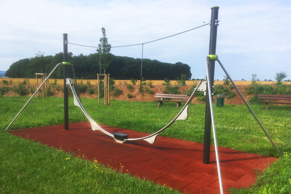AeroSkate Balancier- und Gleitspielgerät auf dem Spielplatz Eisenach-Hötzelsroda mit Fallschutzfläche und naturnaher Umgebung.