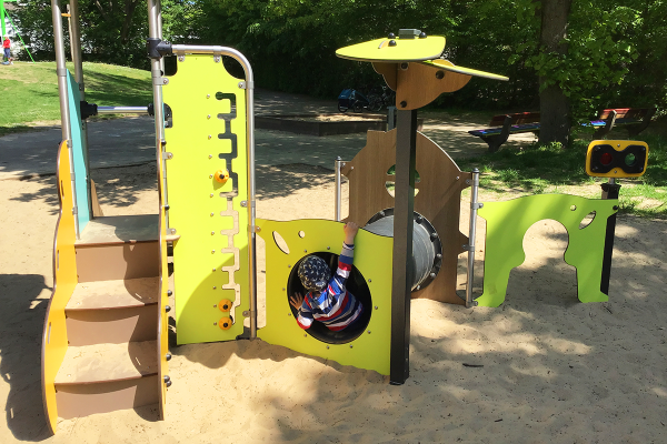Kleinkind spielt im Diabolo Baby Spielgerät mit Tunnel, Stufen und Spielelementen auf dem Spielplatz Maiwiese in Herford.