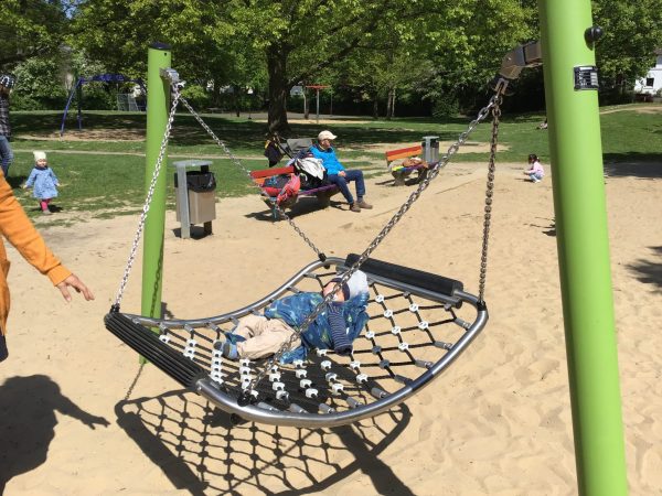 Kind liegt auf einer Nestschaukel „Fliegender Teppich“ auf dem Spielplatz Maiwiese in Herford.