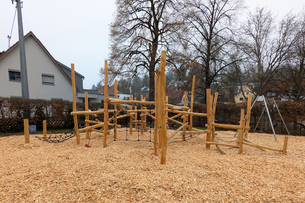 Großzügiger Balancier- und Kletterparcours aus Naturholz mit Seilelementen auf einem Spielplatz in Nürtingen, umgeben von Wohnhäusern und Bäumen
