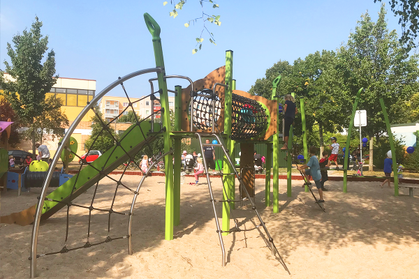 Kinder spielen auf einer Kanopé-Kletteranlage mit Netzbrücken, Kletterelementen und Rutsche auf einem Sandspielplatz in Rostock