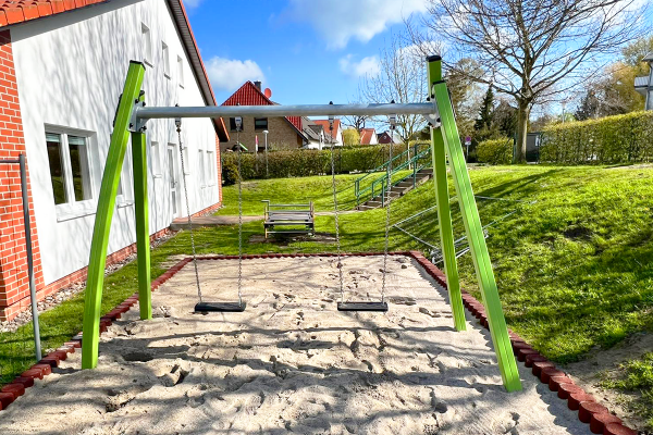 Doppelschaukel mit zwei Sitzen auf Sandfläche im Außengelände der Kita Kunterbunt Prohn