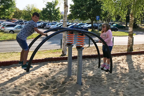 Zwei Kinder spielen auf einer Stehwippe mit Federmechanismus auf einem Sandspielplatz in Rostock