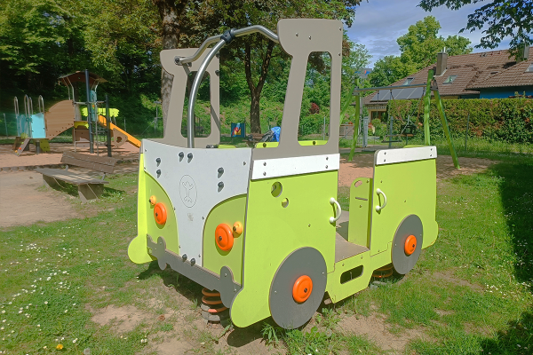 Federspielgerät in Fahrzeugoptik auf einem öffentlichen Spielplatz in Gersthofen mit Spielanlage und Schaukel im Hintergrund.