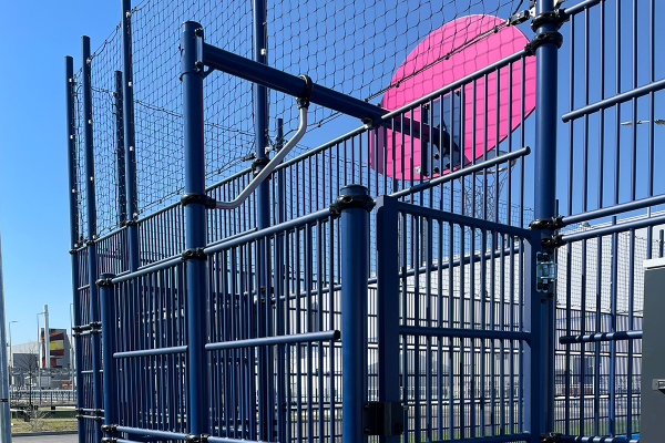 Detailansicht der Ballfangzaunanlage und Basketballkonstruktion der Multisportanlage bei Tesla Grünheide mit pinkem Basketballbrett.
