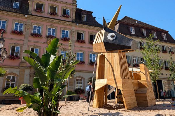 Einhorn-Spielgerät aus Naturholz auf dem temporären Pop-up-Spielplatz am Oberen Marktplatz in Schwäbisch Gmünd. Die Spielskulptur steht in einer großzügigen Sandfläche vor dem historischen Rathaus und lädt Kinder zum Klettern, Spielen und Entdecken ein.
