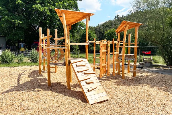 Individuelle Holzspielanlage mit Kletterrampe, Kletternetz, Tunnel und erhöhten Podesten im Kinderhaus Montessori Sonnenhaus in Maxhütte-Haidhof.
