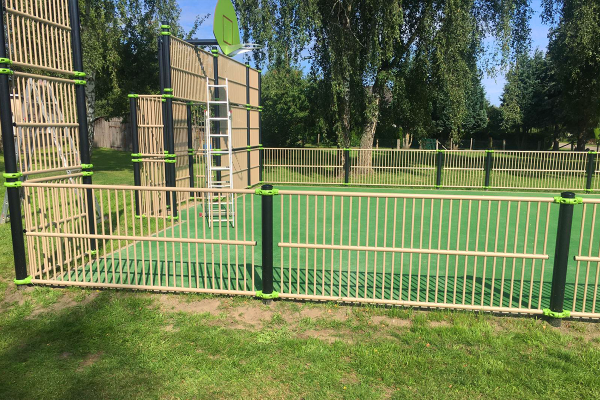 Detailansicht der Multisportanlage in Finkenthal mit Basketballkorb, Ballfangwänden und eingezäuntem Spielfeld in grüner Parkumgebung.