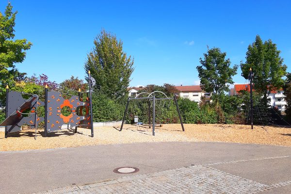 Panorama des Spielplatzes am Kulturzentrum Leingarten mit Kletterparcours, Tampenschaukel und Netz-Pyramide in naturnaher Umgebung.
