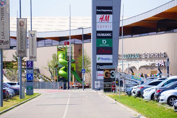 Blick auf den Kanopé-Spielturm von Proludic im Außenbereich des G3 Shopping Resorts in Gerasdorf bei Wien, sichtbar vom Parkplatz des Einkaufszentrums.