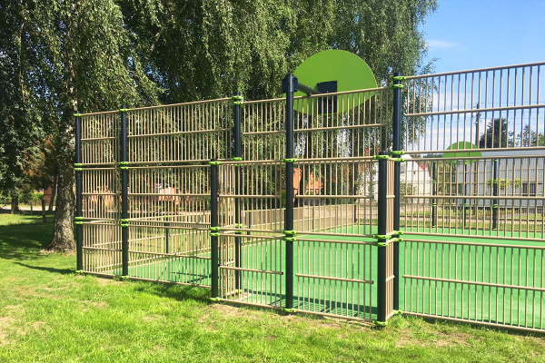Multisportanlage in Finkenthal mit hoher Ballfangwand, Basketballkorb und eingezäuntem Spielfeld in parkähnlicher Umgebung.