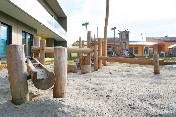 Wasserspielanlage aus Naturholz mit Sandbereich auf dem Außengelände der Kita Karlskron zur Förderung von sensorischem und kreativem Spielen.