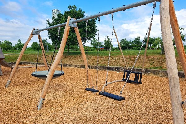 Schaukelkombination mit Nestschaukel, Standardschaukel und Kleinkindersitz auf dem Spielplatz im Himmelsgarten Schwäbisch Gmünd. Die Anlage aus Naturholz bietet altersgerechte Spielmöglichkeiten für Kinder verschiedener Altersgruppen.